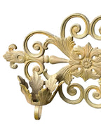 Decorative gold metal wall bracket on a gray surface