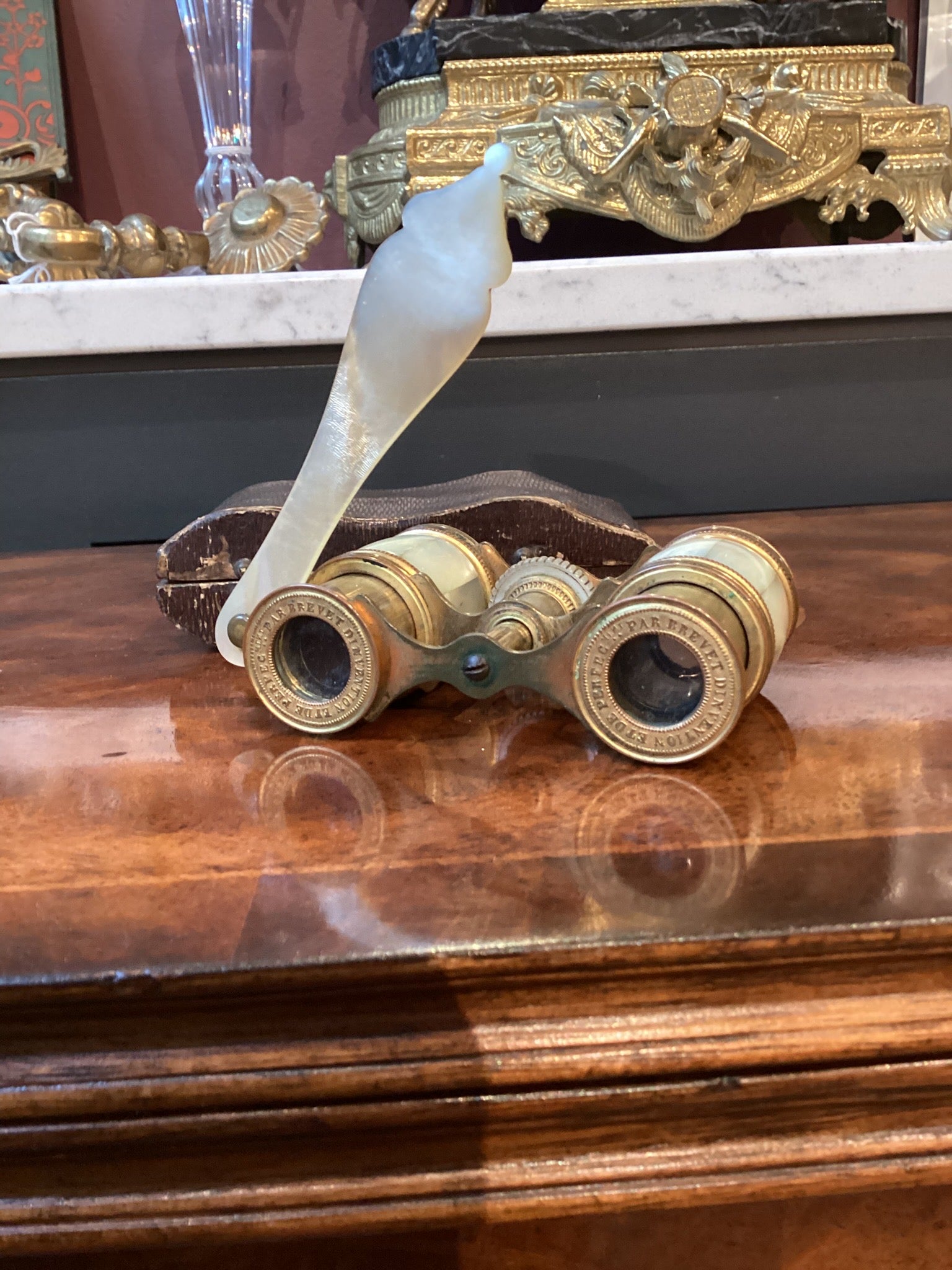 Vintage binoculars with a decorative white bird on top, placed on a wooden surface.