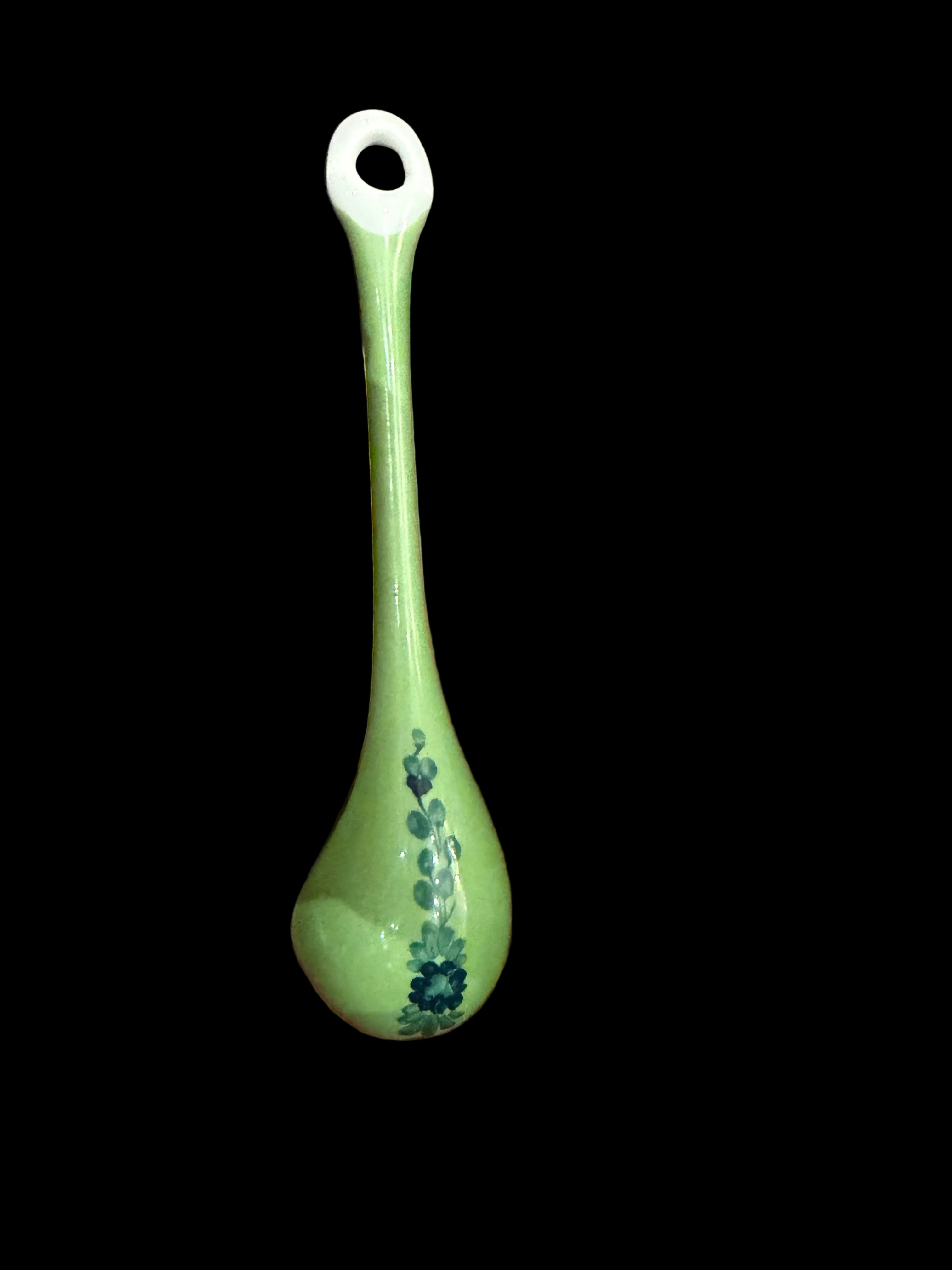 Green ceramic spoon with floral patterns on a wooden surface