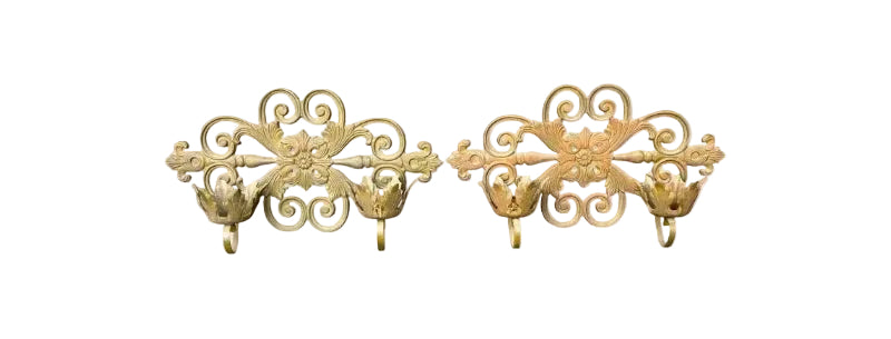 Two gold decorative wall hooks on a white background